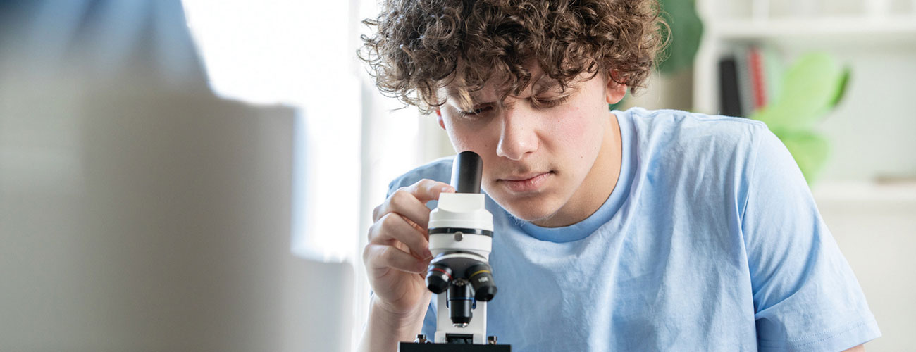 A male student looking through a microscope